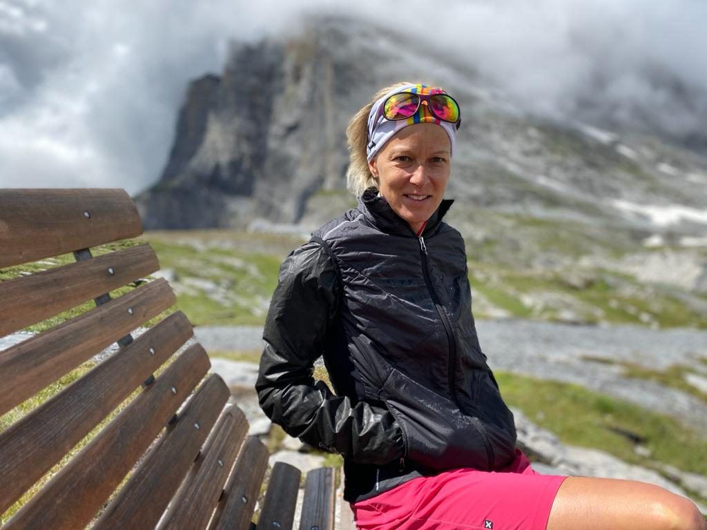 Laetitia Marchand assise sur un banc en montagne, en tenue de sport, regarde l’objectif