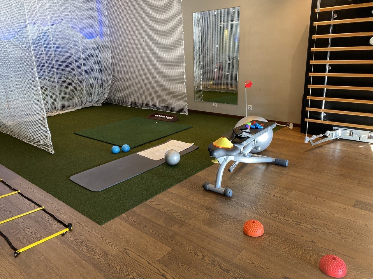 Une salle d’entraînement avec tapis, ballons, échelle de rythme, rameur et espalier