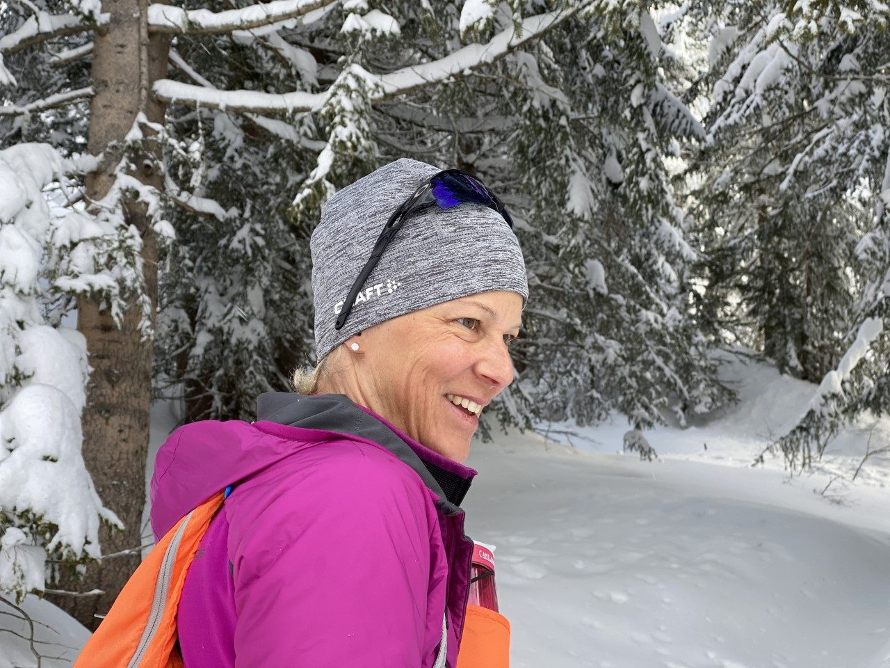 Laetitia Marchand, souriante, de profil, en bonnet et veste de sport dans une forêt enneigée